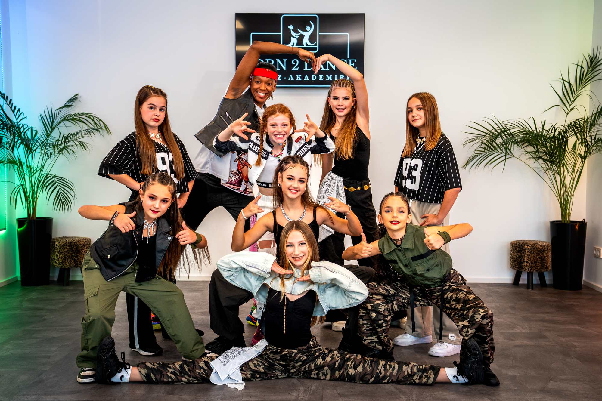 Born 2 Dance Hip-Hop-Tanzgruppe mit Trainerin posiert im Tanzstudio in lässigen Streetwear-Outfits